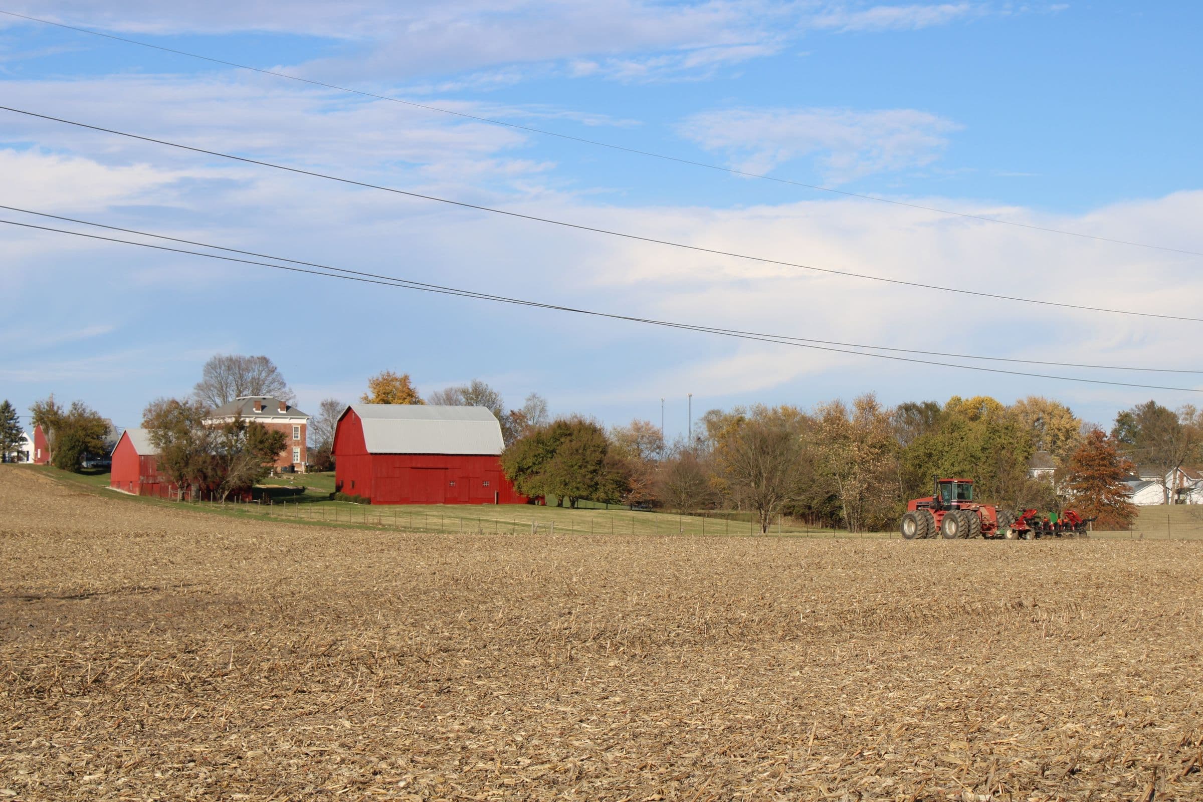 Red barn and farmhouse beside a harvested field with a tractor near Clinton NC