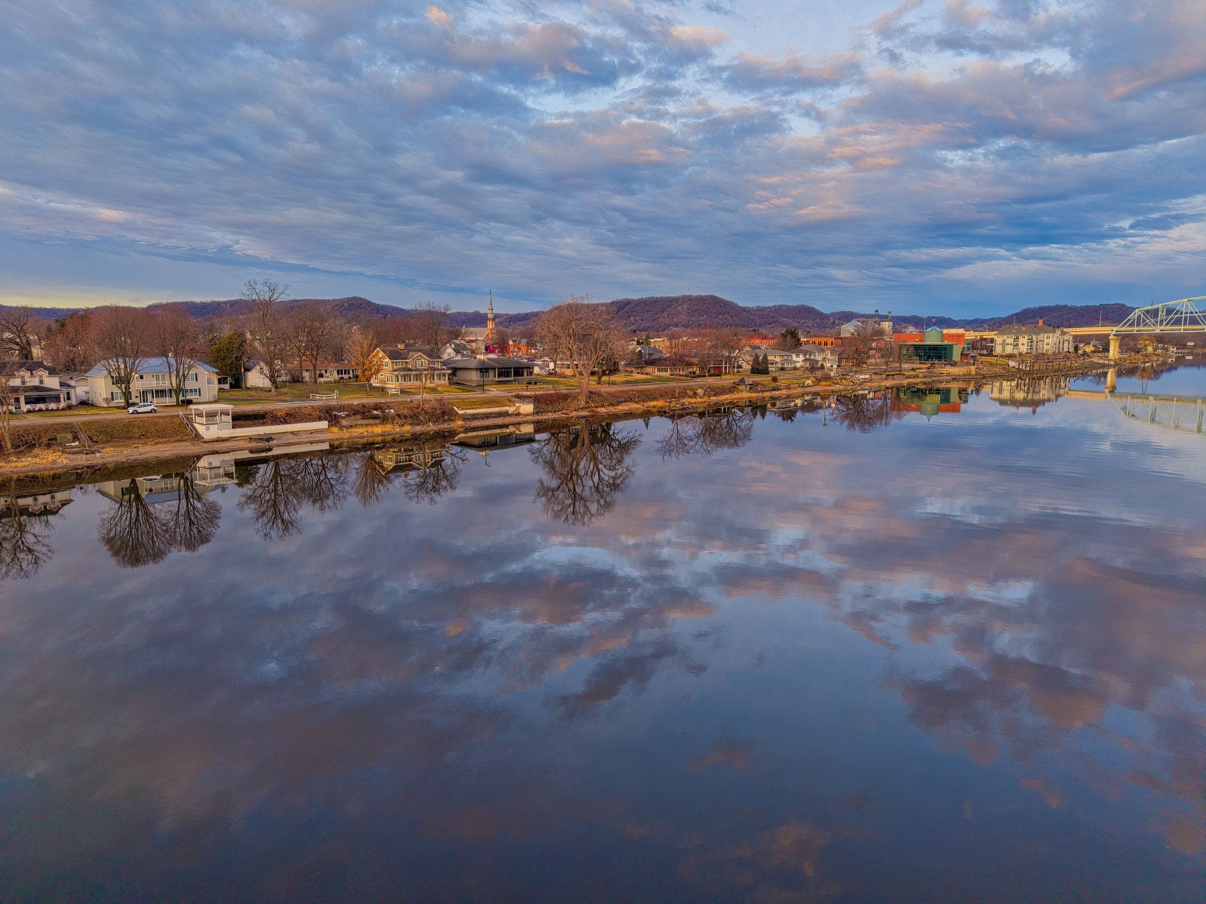 Calm river reflecting a cloudy sky beside a small riverside town like Lillington NC