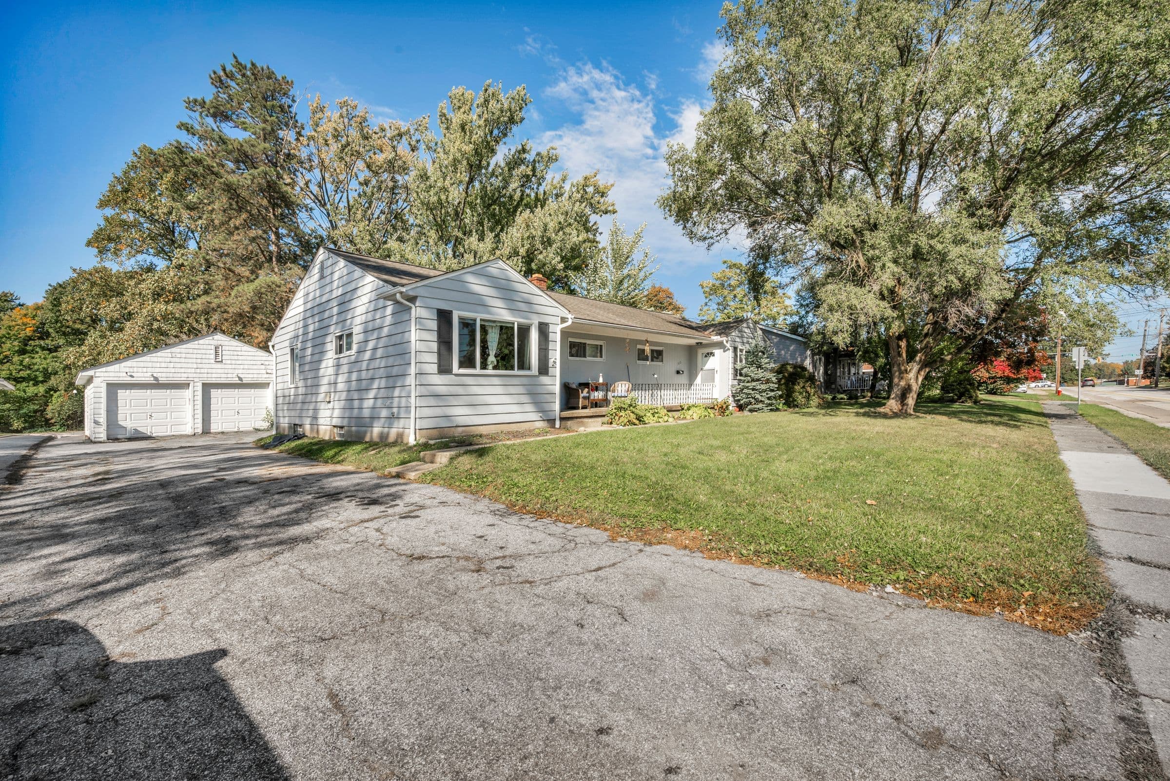 White ranch house with a detached two-car garage and a wide asphalt driveway like homes in Spring Lake NC