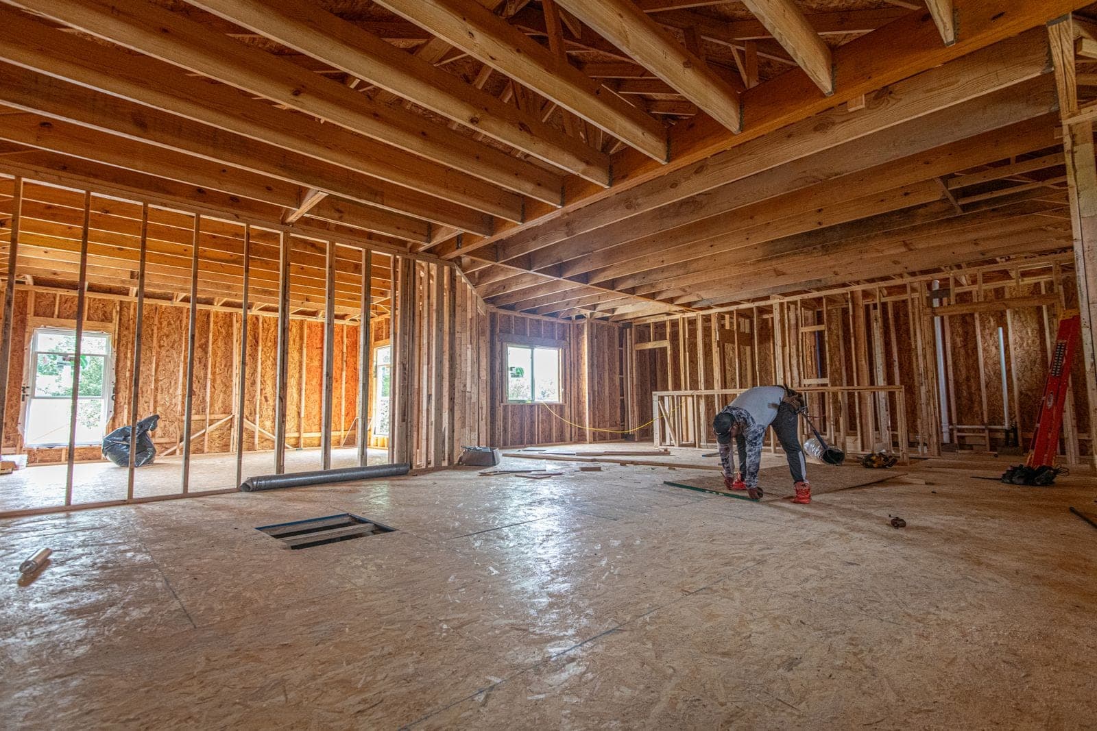 Contractor laying subfloor inside a framed house under construction