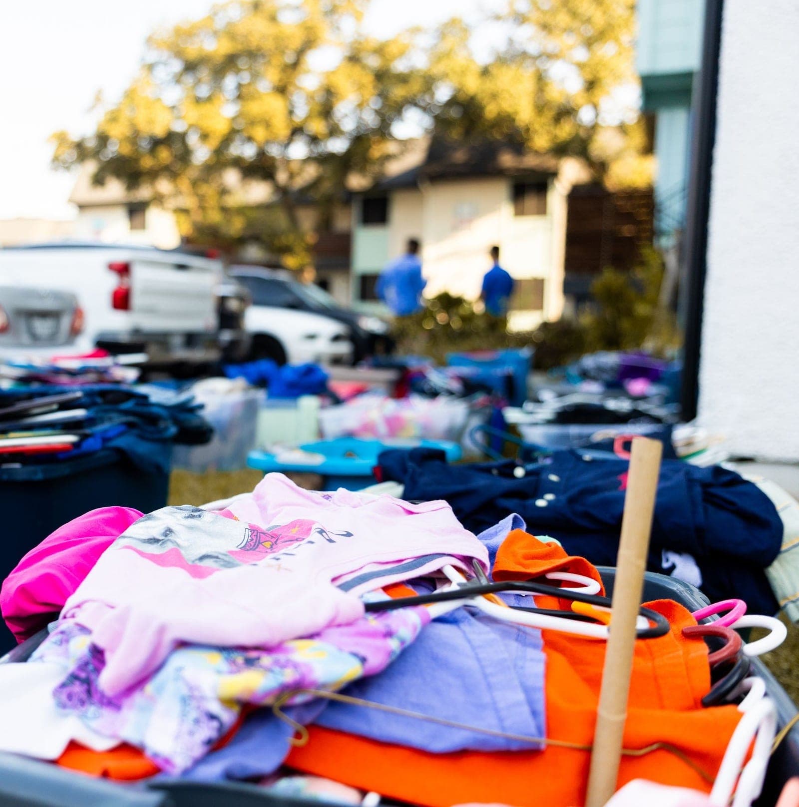 Tables of clothes and household items set out in a driveway during a cleanout and yard sale
