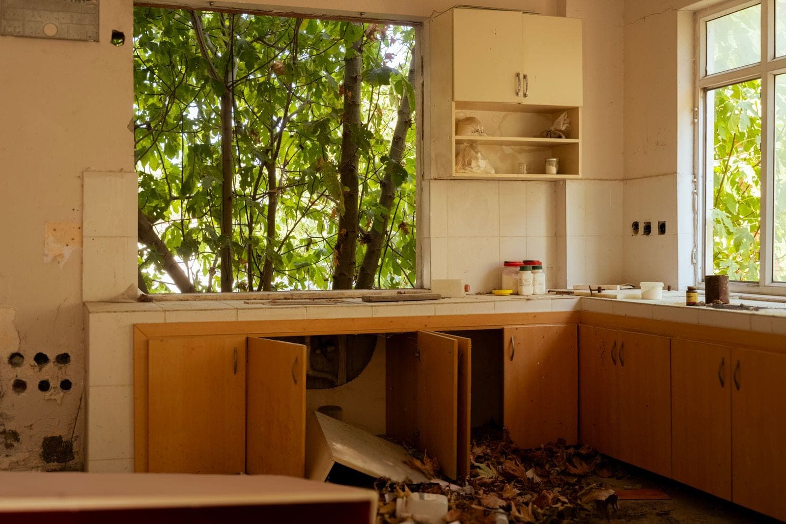 Gutted kitchen with torn-out cabinets and debris on the floor during a remodel