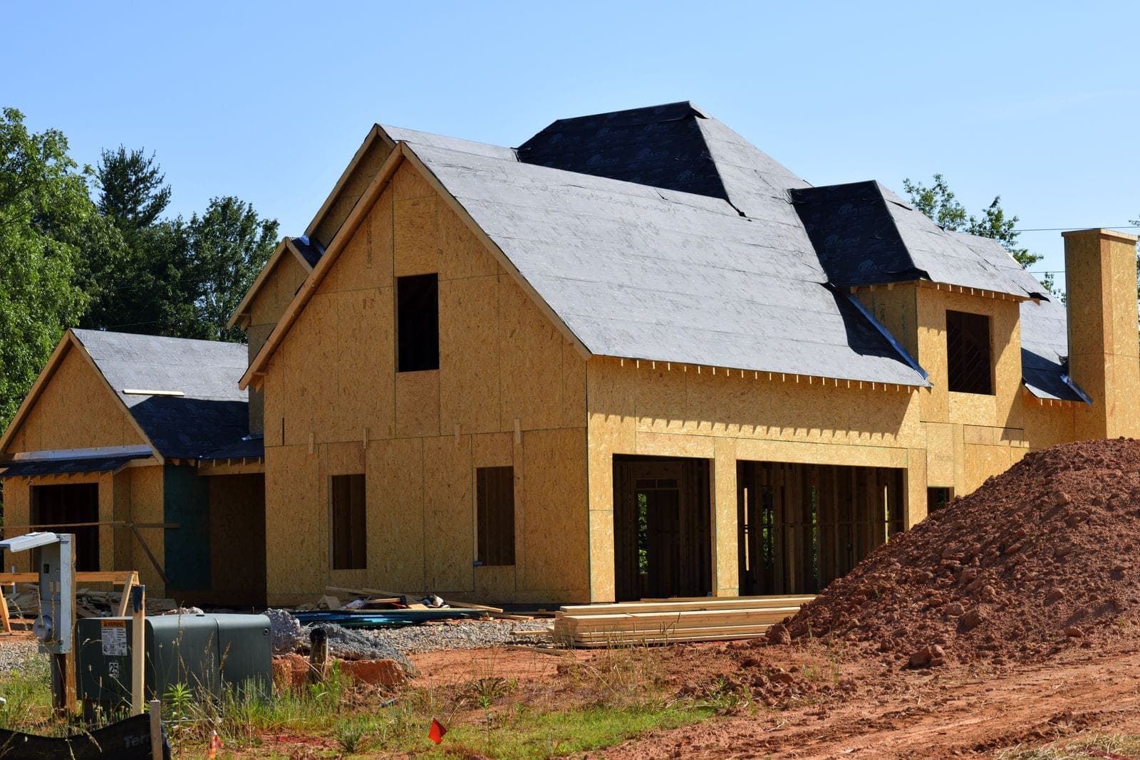 Two-story house framed in OSB sheathing at a new construction site